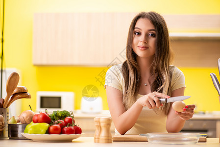 在厨房在家做沙拉的年轻女青年饮食勺子蔬菜微笑营养午餐女士美食围裙木板维他命高清图片素材