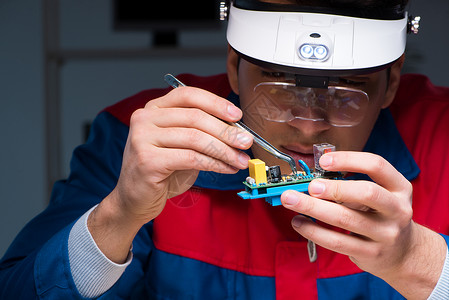 计算机专家在深夜修理个人电脑中心焊接处理器母板眼镜螺丝刀木板硬件工人安装翻新高清图片素材