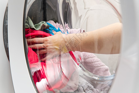 观真门玻璃 女人双手从洗衣机里取出要洗的衣服 女人把衣服放在洗衣机里 选择性的焦点浴衣高清图片素材