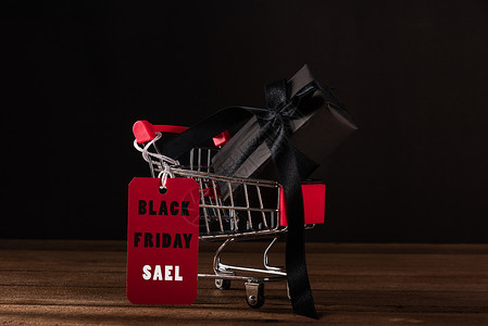 彩带标签在店里用黑纸和黑色弓彩带包着的礼品盒礼物销售标签惊喜红色盒子商业篮子购物大车背景