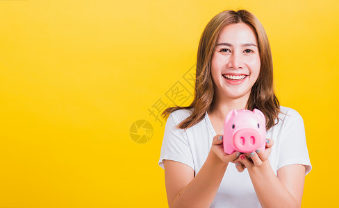 拿着黄线猪女人笑着拿着一大笔钱的猪银行女孩小猪经济金融债务推杆投资者银行业储蓄牙齿背景