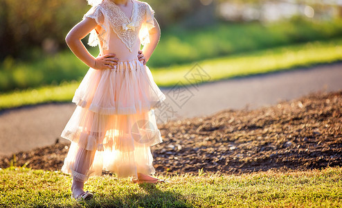 快乐的年轻女孩在一花园后光暗中游女性裁剪孩子姿势青年幸福创造力裙子童年生长背景图片