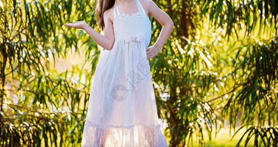 快乐的年轻女孩在一花园后光暗中游青年孩子生长白色童年姿势幸福裁剪创造力绿色背景图片