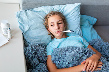 患有高发烧和头痛患病的十几岁少女躺在床上 将温度计放在嘴里疾病治疗毯子病人女孩温度前额保健感染童年青少年高清图片素材
