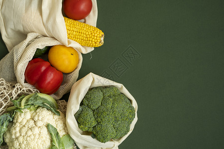 绿色表面生态袋中的蔬菜 带有复制空间 胡椒 西红柿 玉米 黄瓜 西兰花 花椰菜 装在可重复使用的购物环保棉布袋中 零废塑料免费概背景图片