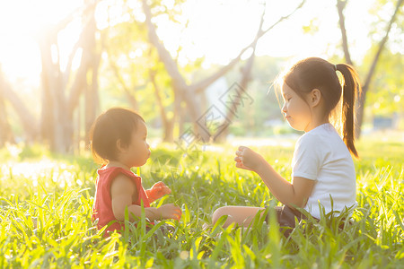 美丽的年青年轻小孩 夏天在公园玩耍的时候坐在公园里闲暇朋友们微笑女孩孩子们姐姐幸福快乐童年晴天亚洲高清图片素材
