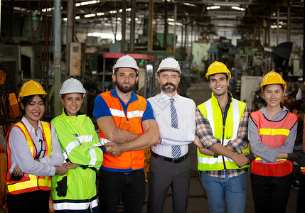 工程师经理组和工厂工人团队站在生产线对面技术员机器创新眼镜安全建筑师两个人头盔服务员工蓝图高清图片素材