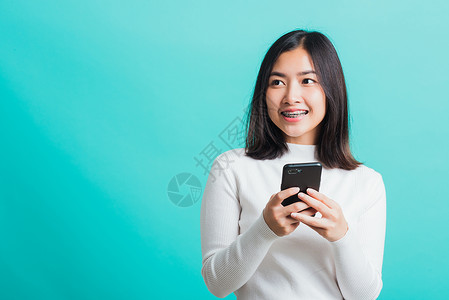 妇女微笑 她拿着并打短信滚动网络女士工具手机技术头发细胞短信互联网乐趣高清图片素材