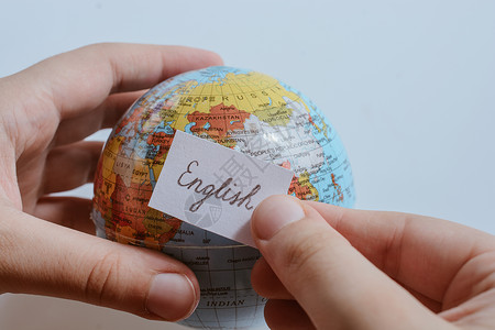 手持全球使用英文文字的纸上随笔纸说话字典班级商业世界地球语法语言文化旅行学习高清图片素材