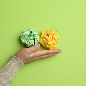 一只雌性手的绿色和黄色圆形纸球背景图片