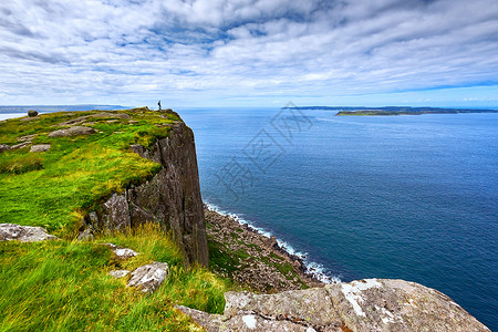 乘客背背包站在悬崖边的旅游者 Fair Head 北爱尔兰 英国旅行女士全景顶峰悬崖女性冒险县城旅游闲暇背景