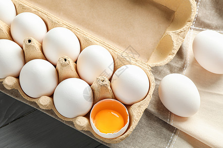 鸡蛋盒子纸箱中的白鸡蛋和木制桌上的厨房毛巾 文字空间和顶视图背景