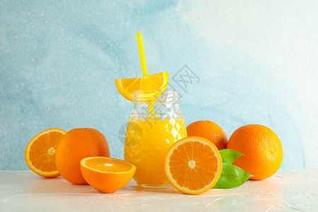 玻璃罐 有新鲜橙汁和小管 白桌上的橙子与彩色背景 文字空间 新天然饮料果汁情调桌子榨汁机早餐薄荷排毒饮食木头水果背景图片