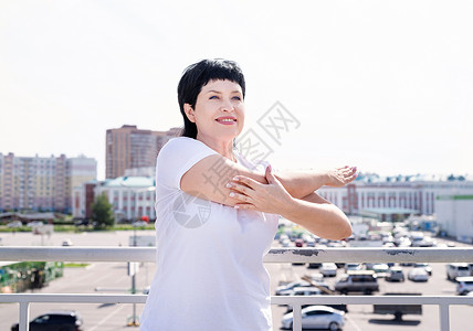 微笑的老年妇女在城市背景上做户外伸展活动运动装运动员运动闲暇退休女性成人身体娱乐力量背景图片