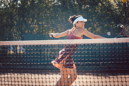 穿红运动服打网球的妇女运动员俱乐部网球场爱好球拍网球乐趣教训法庭女士背景图片
