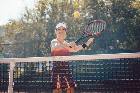 穿红运动服打网球的妇女爱好俱乐部运动场微笑运动球拍运动员网球学习法庭背景图片