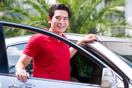 新车开回家亚裔男子站在新车前汽车热带棕榈车辆树木院子男性奢华房子背景