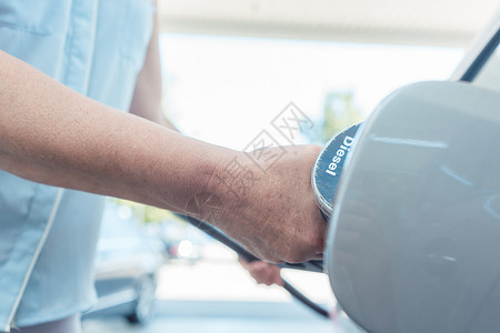 一名高级女子的手被紧贴 她把汽车的油箱装满了福利司机车站长老柴油机汽油老年车辆女性燃料背景图片