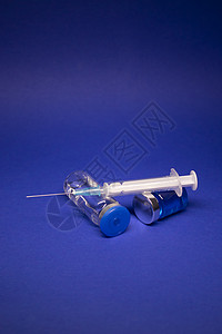 焦三仙两个没有标签的透明疫苗瓶小瓶 医用注射器注射针 在蓝色背景上隔离 冠状病毒疫苗 COVID19 的开发 治愈 世界研究竞赛静脉液背景