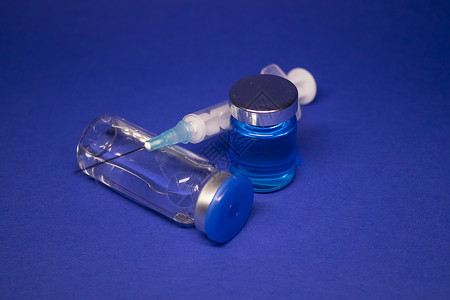 焦三仙两个没有标签的透明疫苗瓶小瓶 医用注射器注射针 在蓝色背景上隔离 冠状病毒疫苗 COVID19 的开发 治愈 世界研究竞赛药理药背景