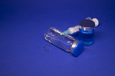 焦三仙两个没有标签的透明疫苗瓶小瓶 医用注射器注射针 在蓝色背景上隔离 冠状病毒疫苗 COVID19 的开发 治愈 世界研究竞赛静脉抗背景