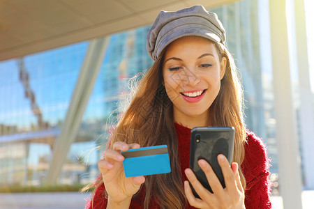 在户外用信用卡买单的 快乐的沙巴女孩的肖像背景图片