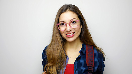 一个带着眼镜和背包站在白色背景上 快乐的无故女学生的肖像白种人高清图片素材