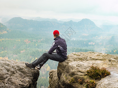 体育运动员在山上岩石边缘放松 享受令人惊叹的景色云雾缭绕高清图片素材