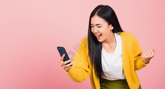 粉色电话使用手机微笑兴奋的少女说是运气游戏玩家学生成人女性女孩互联网乐趣技术背景