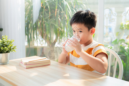 坐着喝水的男孩小可爱男孩 牛奶杯坐在桌子上孩子食物营养白色男生童年微笑饮食玻璃生长背景