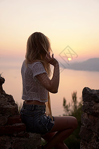 女孩从一个高点看海日落 垂直照片海浪天空阴影日落旅行空气女士岩石成人假期人们高清图片素材