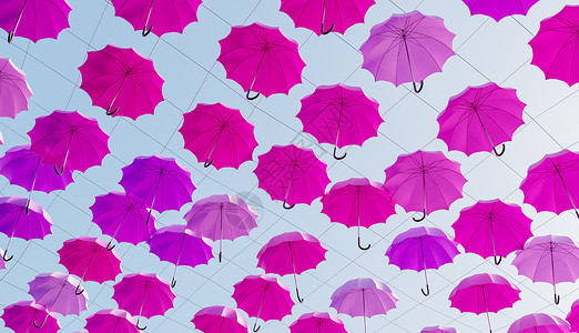 许多粉红色的雨伞挂在树上高清图片