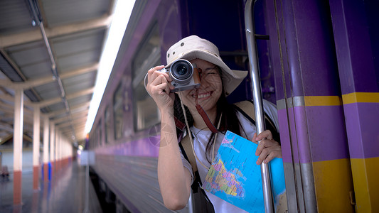 火车上的日落年轻的女游客在等火车旅行时微笑着用相机在火车上拍照旅游摄影 自由积极的生活方式概念背景