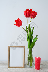 红色花瓶假期模拟 玻璃花瓶中的郁金香花 在家里的木桌背景墙上装饰着相框 特写 母亲节设计理念海报郁金香推介会风格展示嘲笑花束艺术品打印小背景