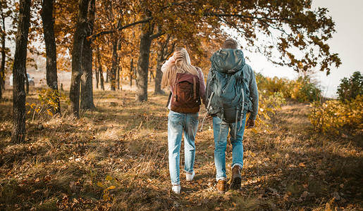 情侣行动毛笔字携着手背包的青年夫妇徒步旅行背景