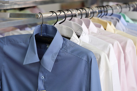 男子在零售商店的衣架上涂着男子衬衫西装裁缝购物洗衣店架子套装壁橱服装团体棉布背景图片
