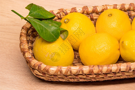 黄色小柠檬小木篮子中的黄柠檬树叶饮食食物黄色圆形柳条桌子白色水果乡村背景