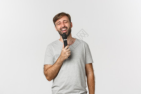 用卡拉OK唱歌 握着麦克风 站在白背景上站着的帅哥们工作室促销男性演讲发型学生胡须成功标识胡子自信的高清图片素材