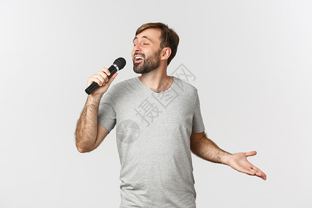 用卡拉OK唱歌 握着麦克风 站在白背景上站着的帅哥们成功学生商业工作室胡子快乐标识情绪衬衫胡须表现高清图片素材