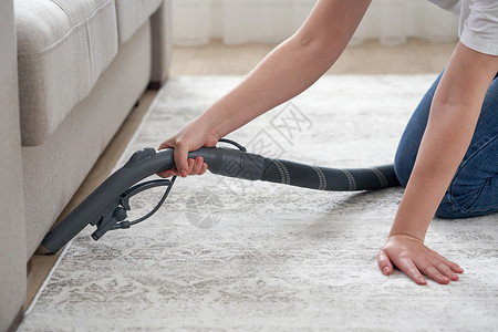 琐事家庭和家务概念 — 快乐的女人或家庭主妇 在家沙发下用吸尘器清洁地板背景