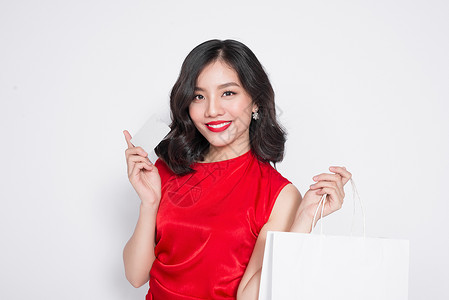 穿着红裙子的漂亮亚洲女人 带着购物袋 拿着信用卡站在白头黑脸上购物者配件礼物销售折扣中心情绪依赖购物店铺季节高清图片素材