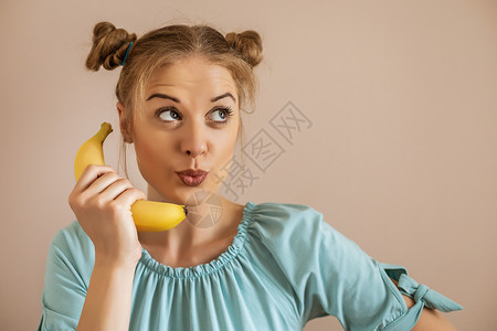 一个黄色香蕉持有香蕉的妇女沉思身体意识活力茶点成人电话食物女性金发女郎背景