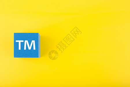 黄色背景蓝色玩具立方体上的 TM 商标标志 带复制空间服务财产专利执照首都金融会计知识分子工作版权抽象的高清图片素材