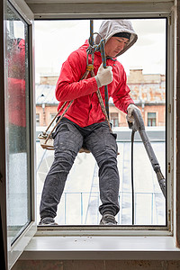 窗户打开时挂着一个攀爬齿轮的窗垫商业办公室工人男人危险职业垫圈工作风险装备背景图片