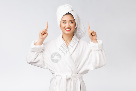 年轻女性的美容肖像显示并指向空空间复制 浴袍中的亚洲美护理化妆品展示广告身体快乐温泉成功皮肤微笑背景图片