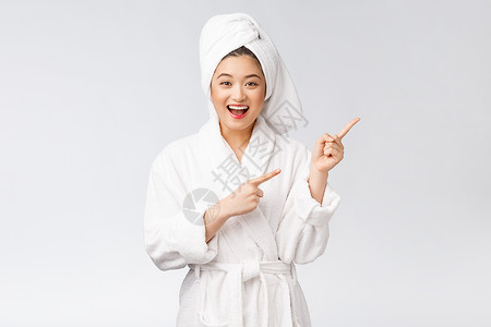 年轻女性的美容肖像显示并指向空空间复制 浴袍中的亚洲美护理温泉化妆品手指治疗身体成功展示微笑浴衣背景图片