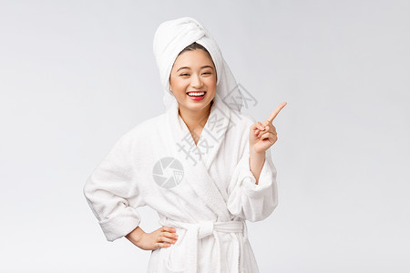 年轻女性的美容肖像显示并指向空空间复制 浴袍中的亚洲美护理温泉女孩广告女士展示成功化妆品微笑手势背景图片