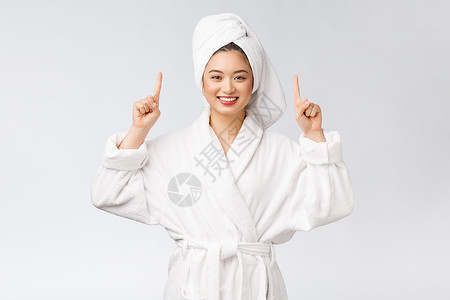 年轻女性的美容肖像显示并指向空空间复制 浴袍中的亚洲美护理广告女孩成功展示皮肤手势手指微笑成人背景图片
