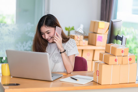 网上兼职素材亚洲女性在办公室使用笔记本电脑和手机上网时很享受 商业和营销以及兼职概念 网上购物和商业成功的主题 愉快的心情做工作杯子技术船运背景