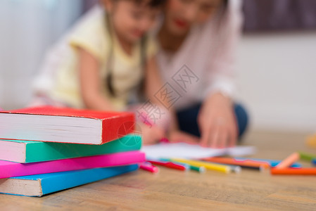 特写地板上的书籍和蜡笔颜色与妈妈和孩子的背景 回到学校和艺术教育学习理念 儿童和老师的主题班级高清图片素材